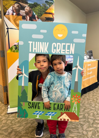 Two kids framed by sign saying 'Think Green'