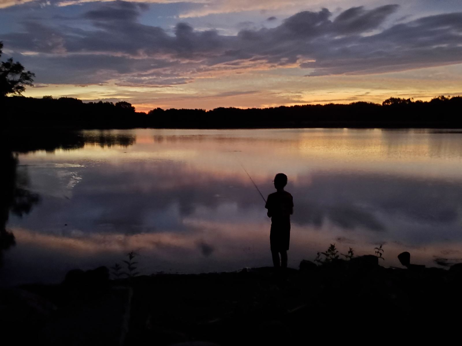 Boy fishing at sunset at Swan Lake