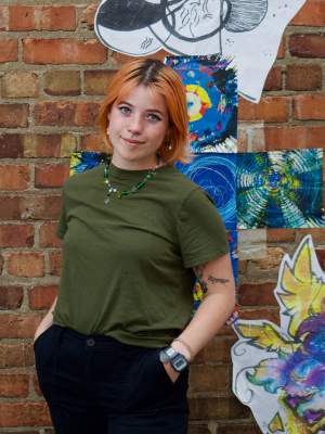 Amelia Whitener in front of a brick wall with colorful art displayed