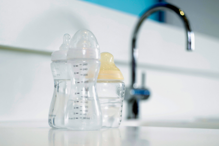 Baby bottles near a faucet