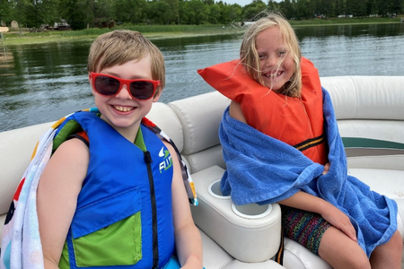 A young boy, left, and young girl, right, in life jackets while boating