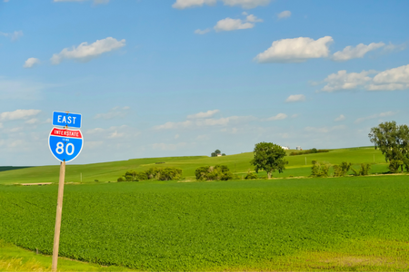 Blue roadsign indicating Interstate 80 with corn field behind