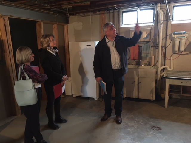 Man pointing to duct work in basement of home during tour