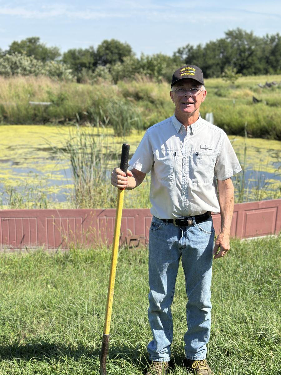 Ray demonstrating the soil test in front of his constructed retention basin.