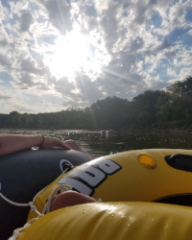 Two river tubes floating down the river into the sun