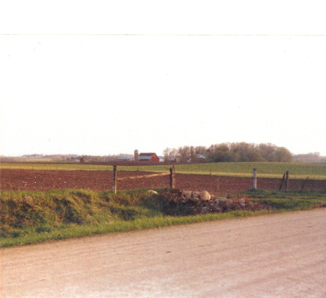 Panoramic view of farm field with red barn and leafless trees