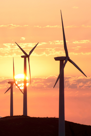 3 wind turbines silhouetted against an orange sunset