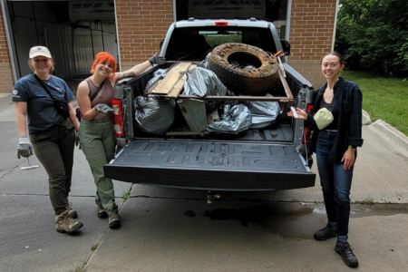 Volunteers next to truck with bed full of trash from clean up